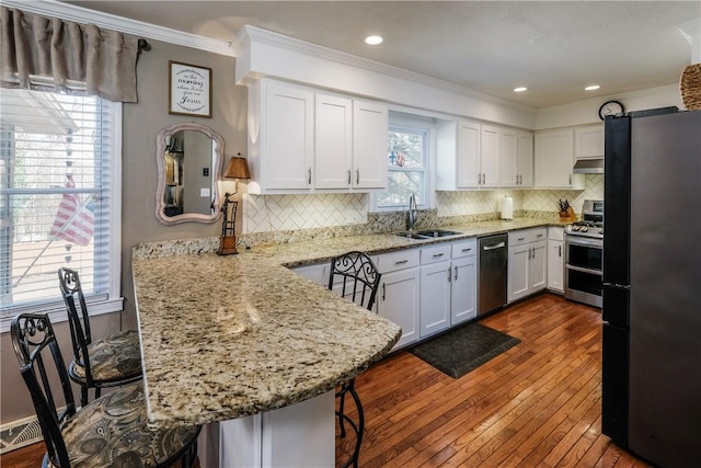 115 Pine Forest Dr, Easley, SC 29642 - kitchen with a sink, under cabinet range hood, white cabinetry, appliances with stainless steel finishes, and a peninsula