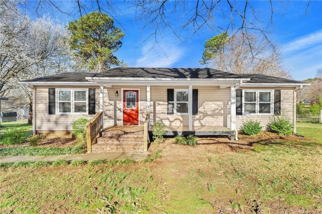 ranch-style house featuring covered porch and a front yard