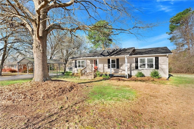 ranch-style home featuring covered porch, a detached carport, and a front lawn