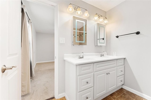 bathroom featuring double vanity, tile patterned flooring, baseboards, and a sink