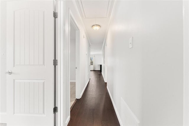 corridor with attic access, dark wood-style floors, and baseboards