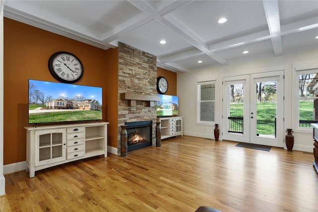 living room with recessed lighting, wood finished floors, coffered ceiling, a stone fireplace, and french doors