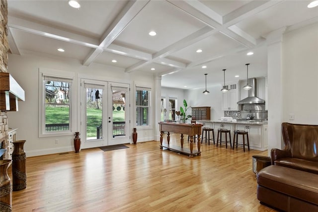 living area with light wood-style floors, beam ceiling, coffered ceiling, and french doors