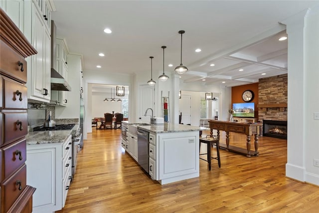 kitchen with a breakfast bar area, stainless steel appliances, light wood-style flooring, and a sink