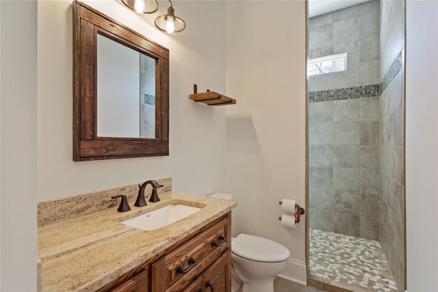 full bathroom with toilet, a tile shower, and vanity
