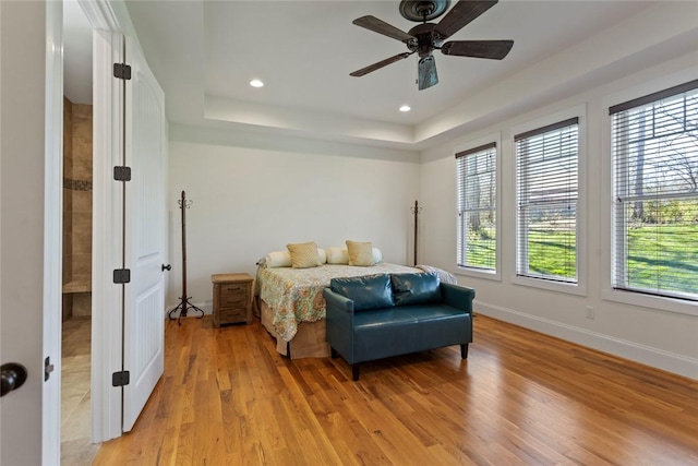 bedroom featuring recessed lighting, ceiling fan, a tray ceiling, light wood-type flooring, and baseboards