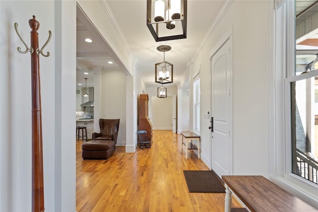 foyer entrance with ornamental molding, baseboards, a chandelier, and light wood-type flooring