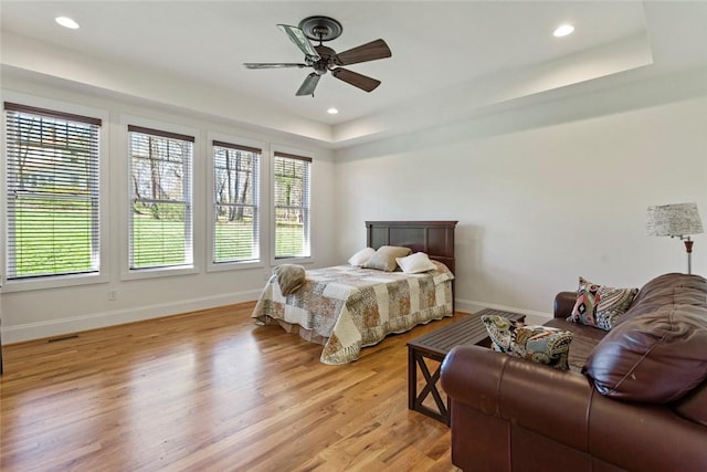 bedroom with recessed lighting, light wood-style floors, ceiling fan, baseboards, and a raised ceiling