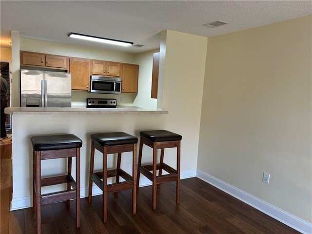 621 Lookover Dr, Anderson, SC 29621 - kitchen featuring appliances with stainless steel finishes, dark wood-style flooring, a breakfast bar area, light countertops, and a peninsula