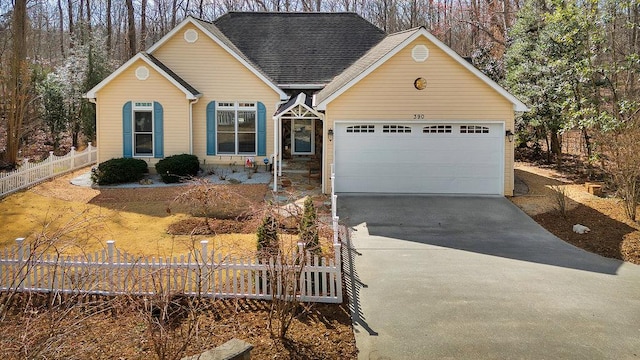 view of front of home featuring driveway, a garage, fence, and a shingled roof