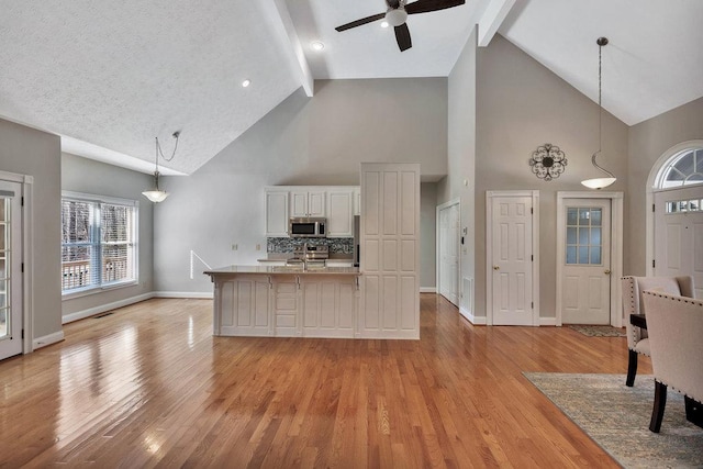 kitchen with light wood finished floors, a ceiling fan, beam ceiling, and stainless steel appliances