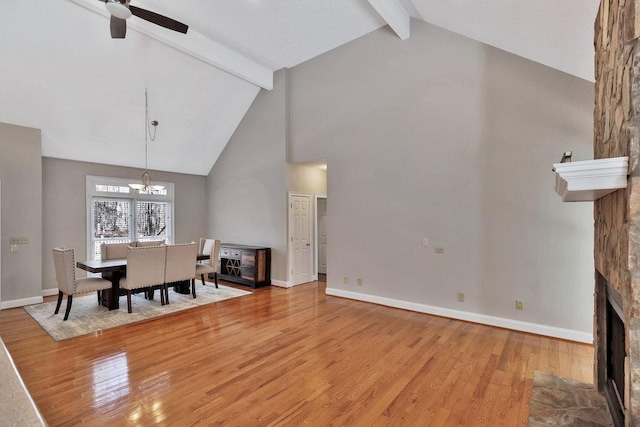 dining area featuring beamed ceiling, a fireplace, baseboards, and light wood-type flooring