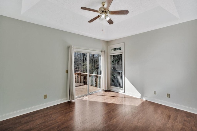 spare room featuring baseboards, a textured ceiling, wood finished floors, and a raised ceiling