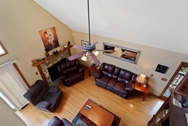 living area with baseboards, lofted ceiling, wood finished floors, and a ceiling fan