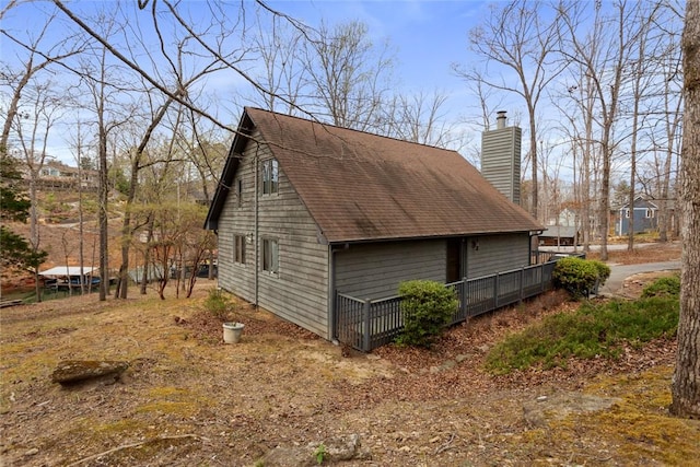 view of property exterior with a shingled roof and a chimney