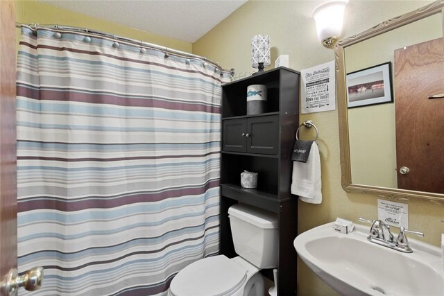 full bath with a textured ceiling, a sink, toilet, and curtained shower