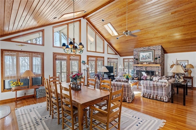 dining room with wooden ceiling, wood finished floors, a skylight, and a brick fireplace