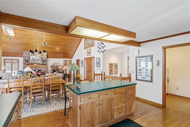 kitchen featuring light wood finished floors, vaulted ceiling with beams, a center island, and baseboards