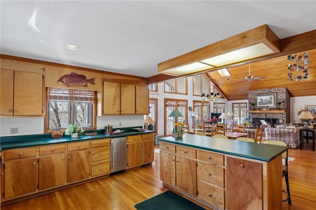 kitchen featuring lofted ceiling, dishwashing machine, dark countertops, and plenty of natural light