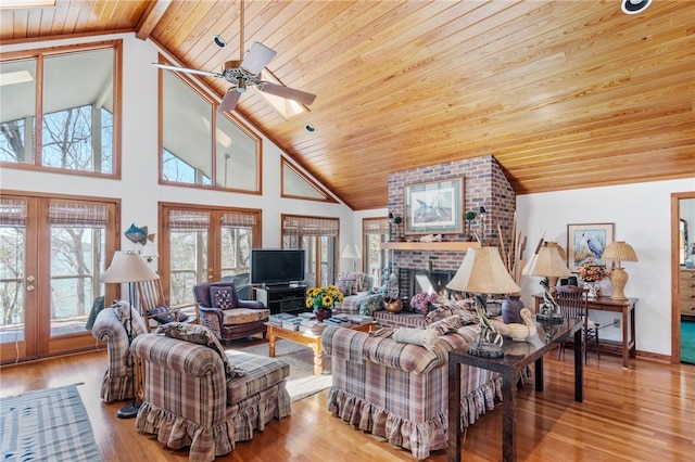 living area featuring high vaulted ceiling, wooden ceiling, a fireplace, wood finished floors, and ceiling fan