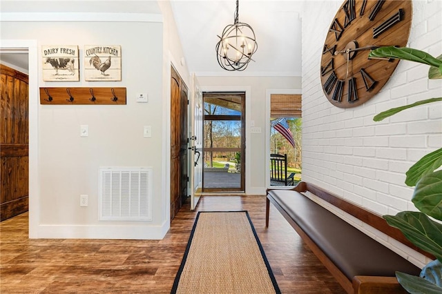 entryway featuring baseboards, visible vents, an inviting chandelier, brick wall, and wood finished floors