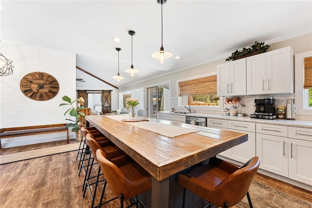 kitchen with light countertops, a breakfast bar, dark wood-style flooring, decorative backsplash, and white cabinetry