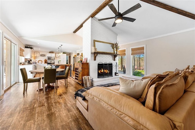 living area with lofted ceiling with beams, a ceiling fan, wood finished floors, and a fireplace