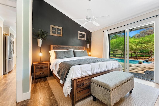 bedroom featuring freestanding refrigerator, lofted ceiling, access to exterior, and wood finished floors