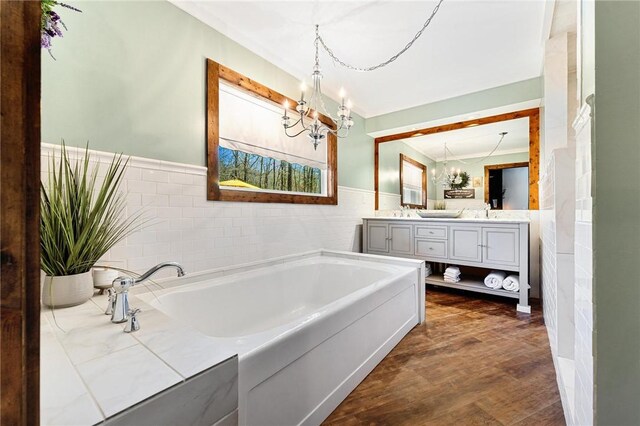 bathroom with a chandelier, tile walls, a garden tub, and wainscoting