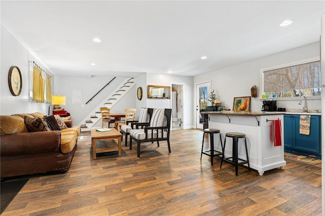 living area with recessed lighting, dark wood finished floors, stairway, and wet bar