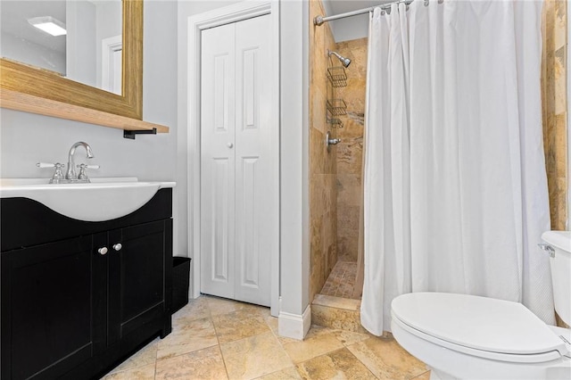 full bathroom with a shower stall, vanity, stone tile flooring, baseboards, and toilet