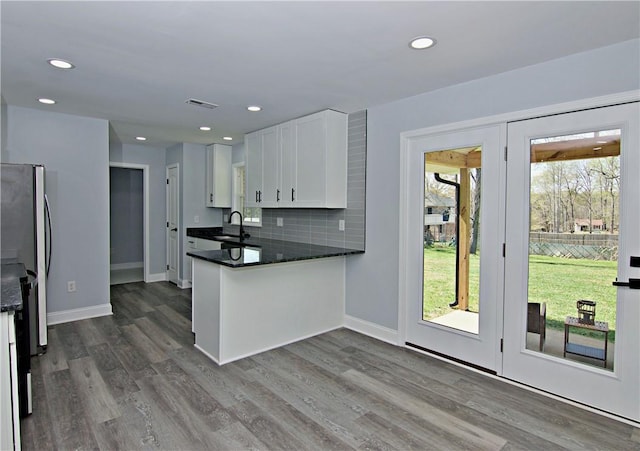 kitchen featuring freestanding refrigerator, white cabinets, tasteful backsplash, and wood finished floors