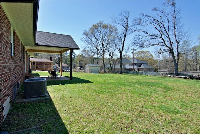 view of yard with an outbuilding, central AC, fence, and a patio area