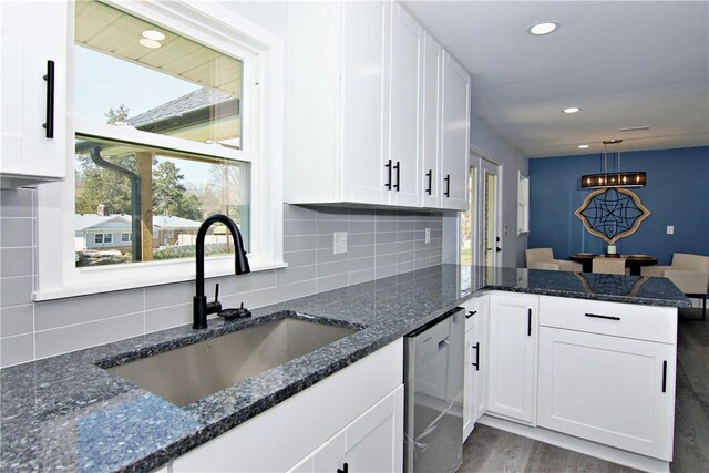 kitchen featuring a sink, tasteful backsplash, wood finished floors, dishwasher, and white cabinets