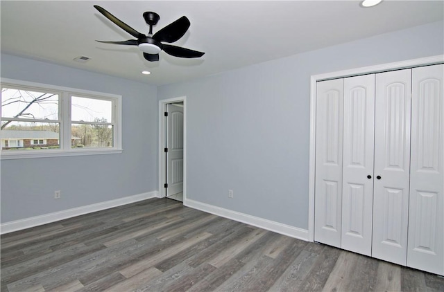 unfurnished bedroom with a closet, wood finished floors, baseboards, visible vents, and ceiling fan