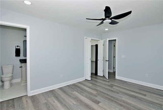 unfurnished bedroom featuring baseboards, connected bathroom, wood finished floors, and recessed lighting