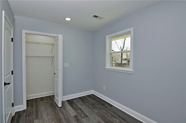 unfurnished bedroom with recessed lighting, dark wood-type flooring, baseboards, visible vents, and a closet