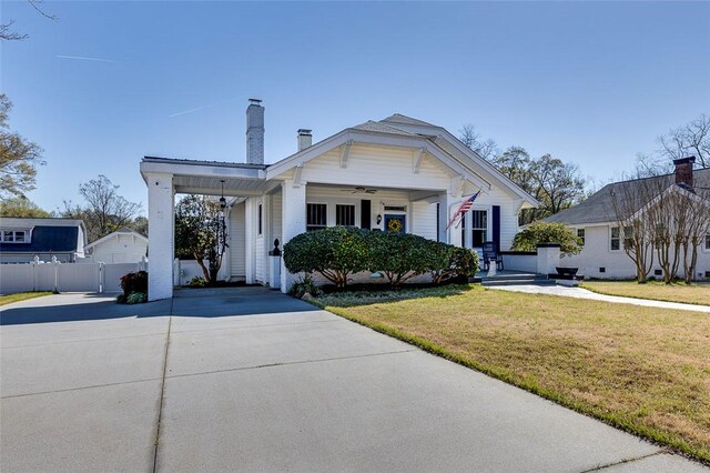 view of front of home with driveway, a front yard, a chimney, fence, and ceiling fan