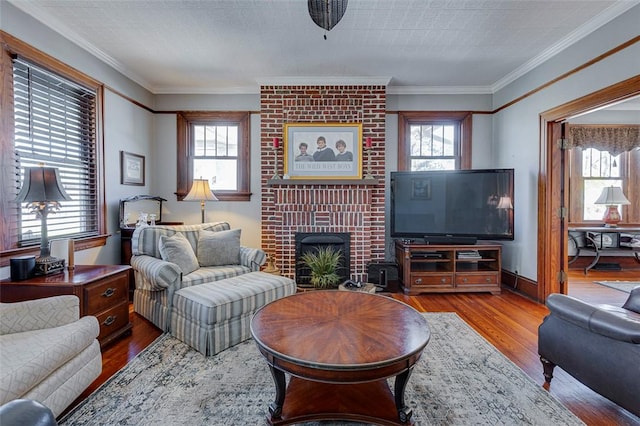 living area featuring a brick fireplace, crown molding, wood finished floors, and a healthy amount of sunlight