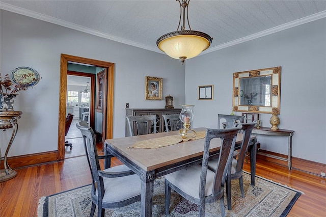dining area with baseboards, crown molding, and wood finished floors