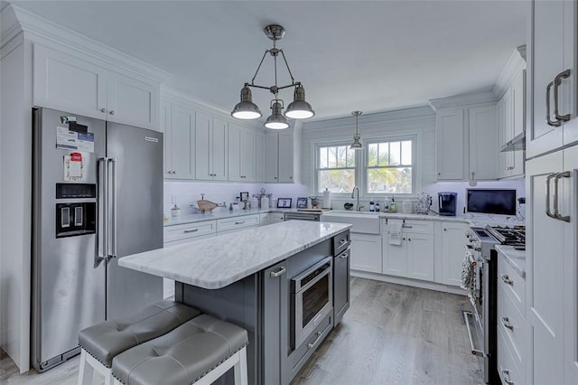 kitchen featuring a sink, white cabinetry, a kitchen bar, and appliances with stainless steel finishes