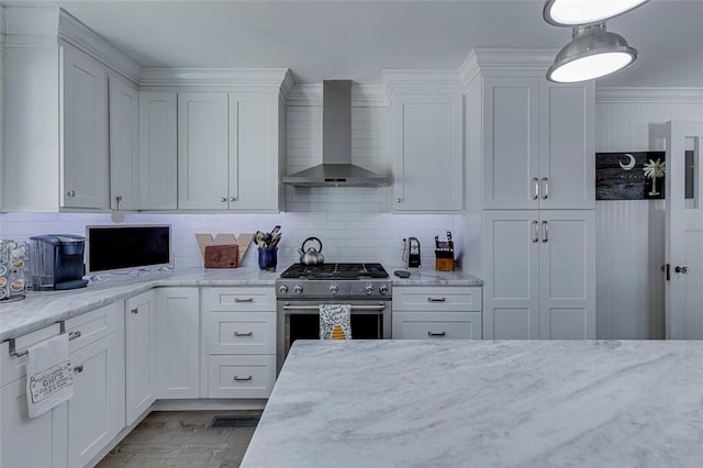 kitchen featuring backsplash, white cabinetry, wood finished floors, wall chimney range hood, and stainless steel range with gas cooktop