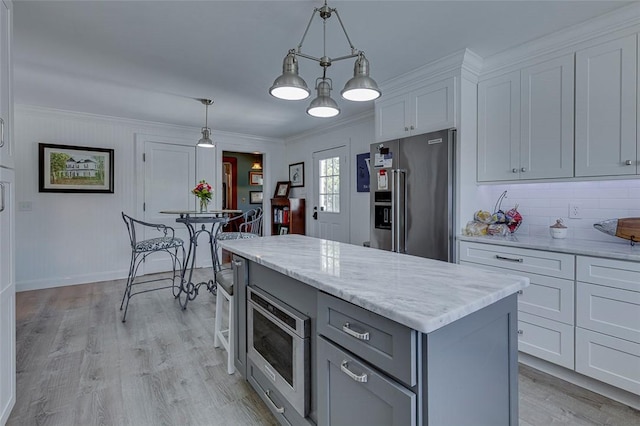 kitchen with gray cabinetry, stainless steel appliances, light wood-style floors, and crown molding