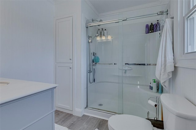 full bathroom with a stall shower, crown molding, toilet, vanity, and wood finished floors
