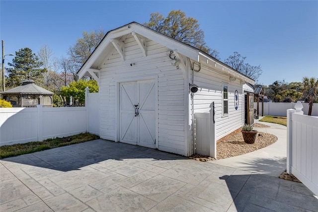 view of outbuilding featuring a fenced backyard, an outdoor structure, and a gazebo