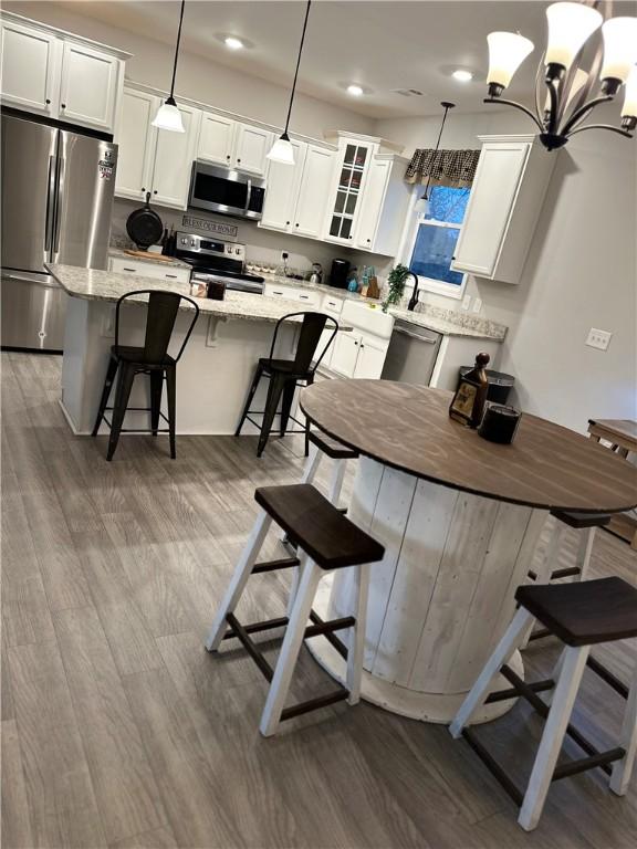 kitchen featuring appliances with stainless steel finishes, a center island, white cabinetry, a kitchen bar, and dark wood-type flooring