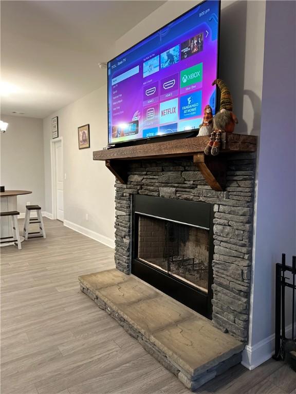 detailed view of a fireplace, baseboards, and wood finished floors