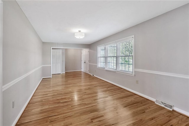 empty room with light wood-style flooring, baseboards, and visible vents