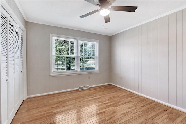 unfurnished bedroom featuring a closet, ornamental molding, visible vents, and light wood-style floors