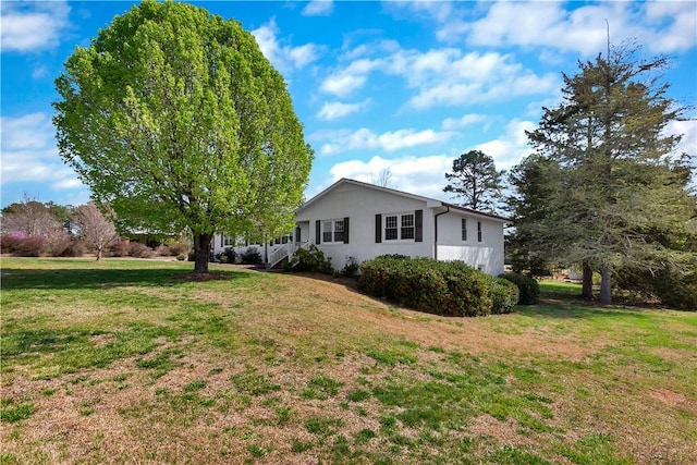 view of side of property featuring stucco siding and a yard